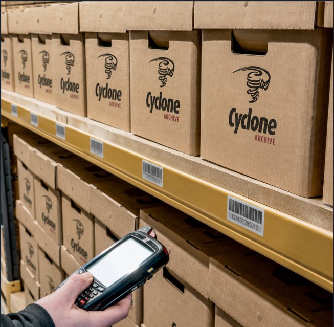 A handheld scanner reading the barcode on a shelf position, with barcoded Cyclone Archive boxes stored above and below